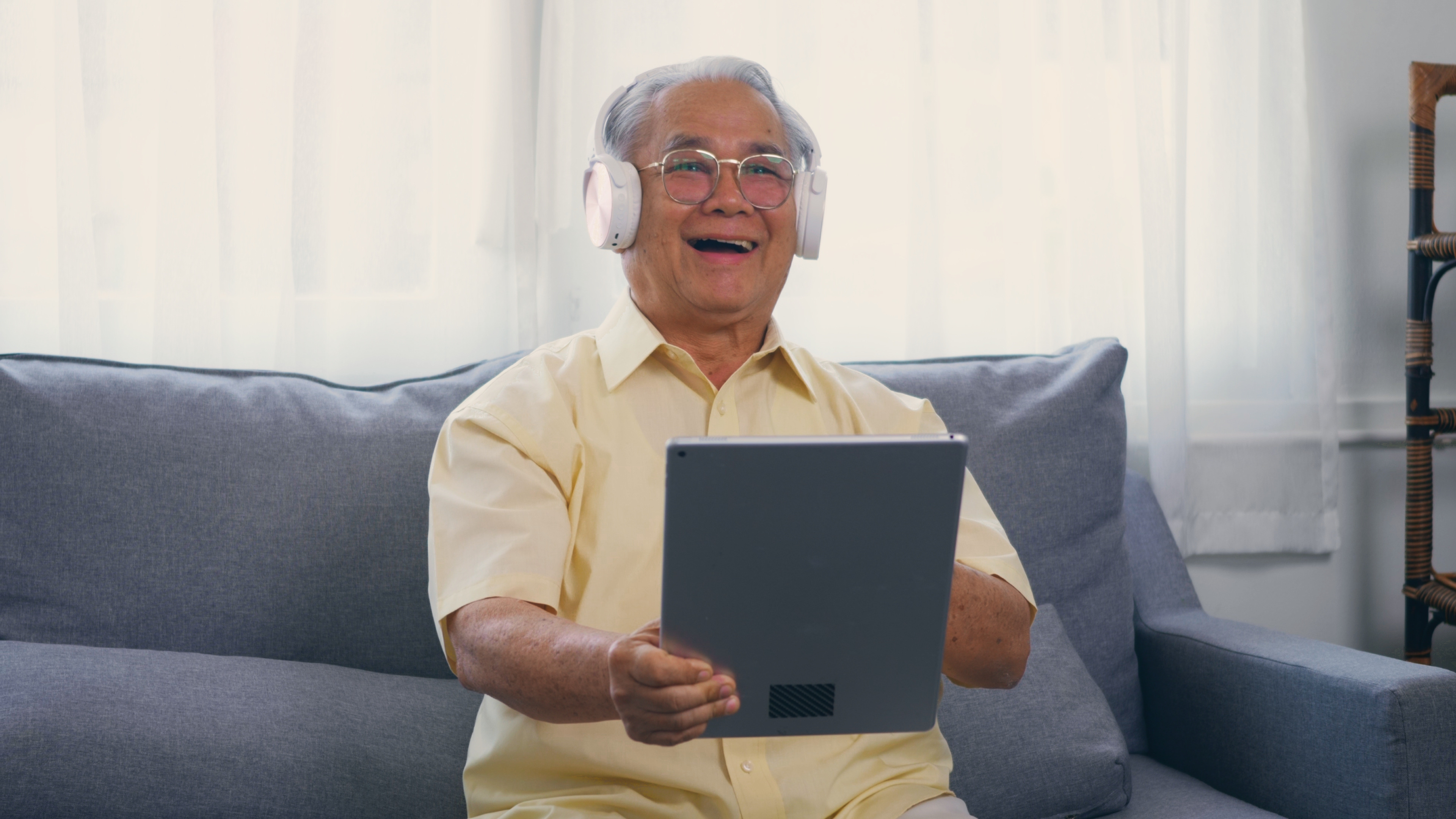 祖父微笑带着眼镜放松戴耳机听音乐使用数字平板亚洲快乐的老年白头发