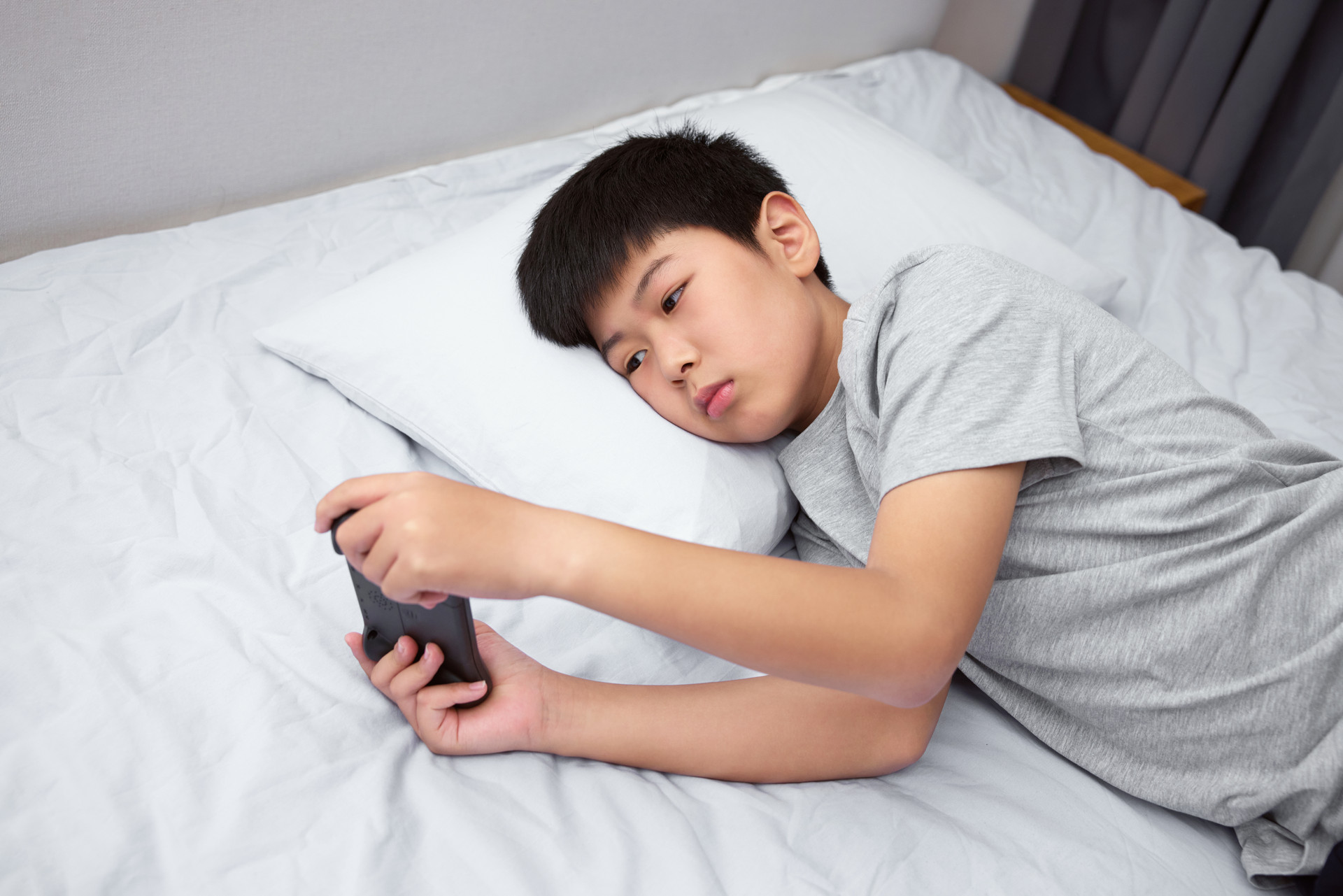 摄图网_507720602_躺在床上打游戏的男孩(企业商用).jpg